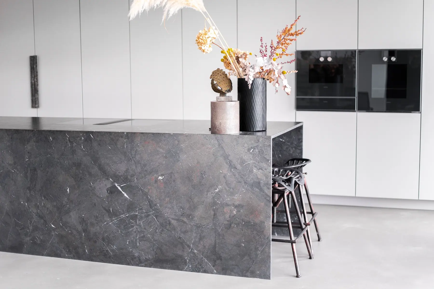 Seitliche Perspektive auf schwarze Küche mit Naturstein – elegantes Zusammenspiel von Form und Material